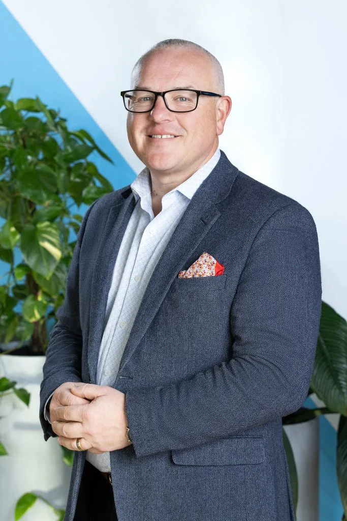 Man in his workplace posing for corporate headshots wearing suit
