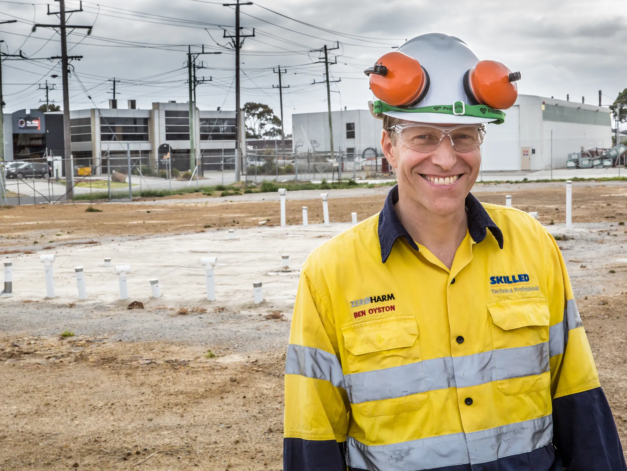 Man on worksite wearing high vis and protective gear posing for environmental portrait